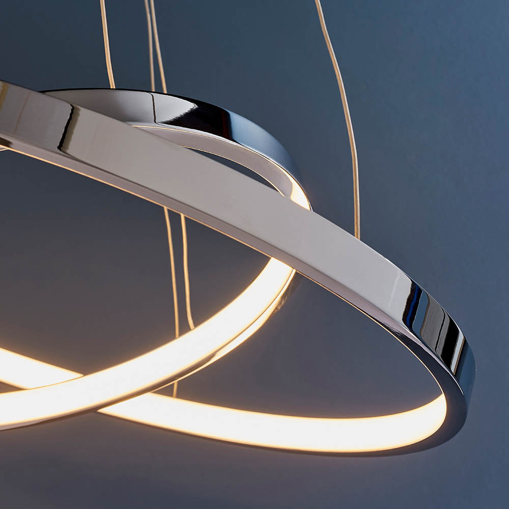Close-up of the chrome finish and warm glow of an LED pendant light's intertwined rings.