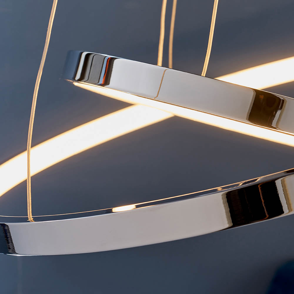 Detailed view of the illuminated chrome rings of an LED pendant light against a dark background.