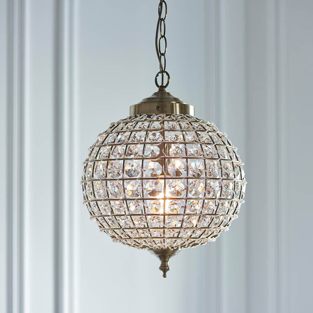 Close-up of a sparkling crystal sphere pendant light with an antique brass finish.