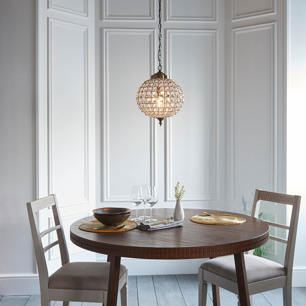 Crystal sphere pendant light illuminating a dining area with a round wooden table and two chairs.