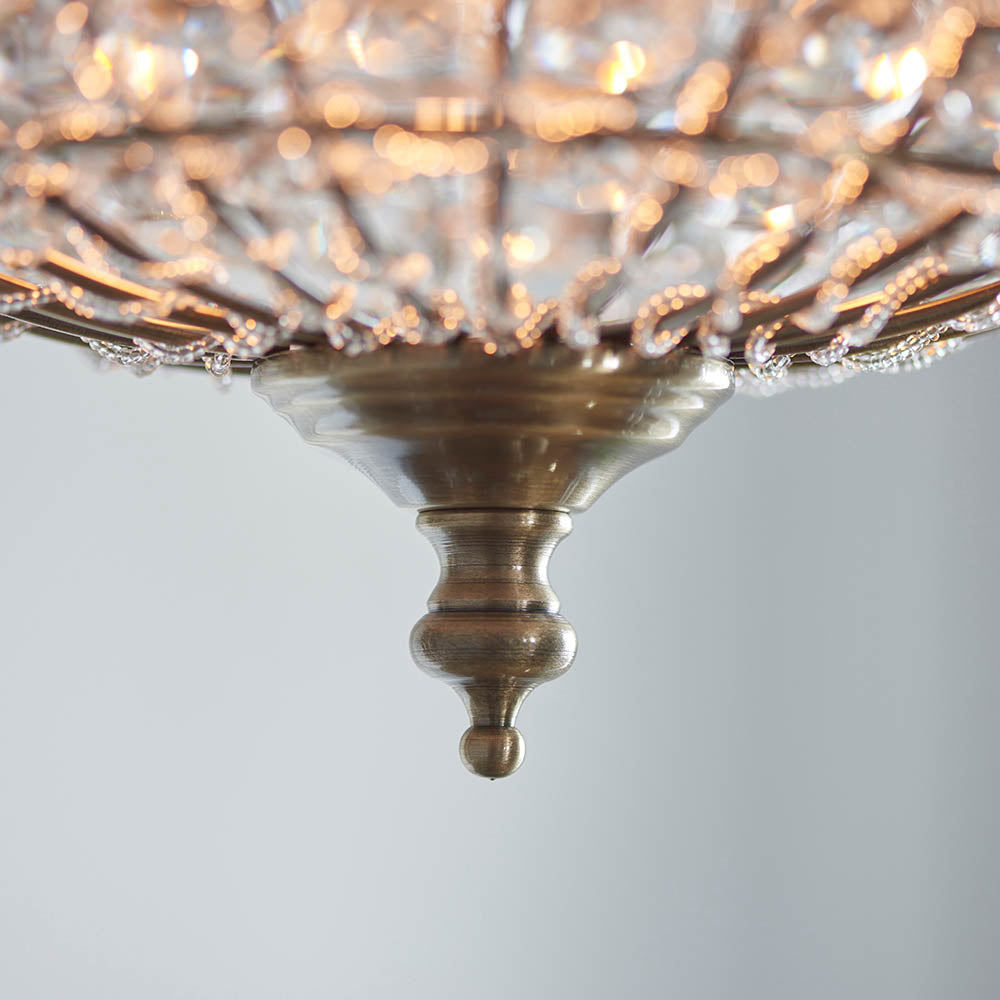 Close-up of the antique brass finial and base of a crystal sphere pendant light.