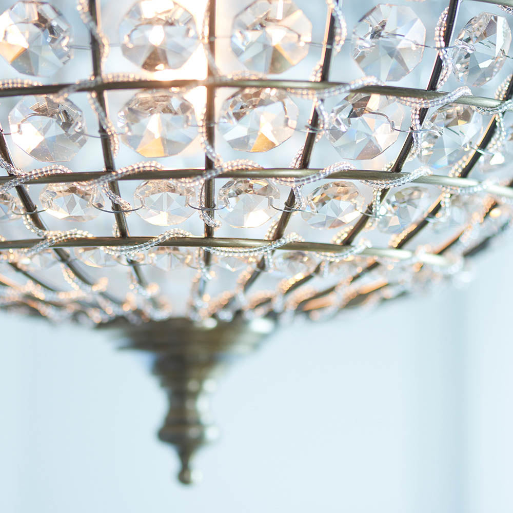 Detailed view of the faceted crystals and antique brass grid of a sphere pendant light.