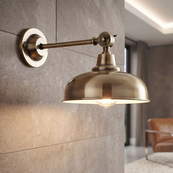 Antique brass wall sconce with a dome shade mounted on a grey stone wall
