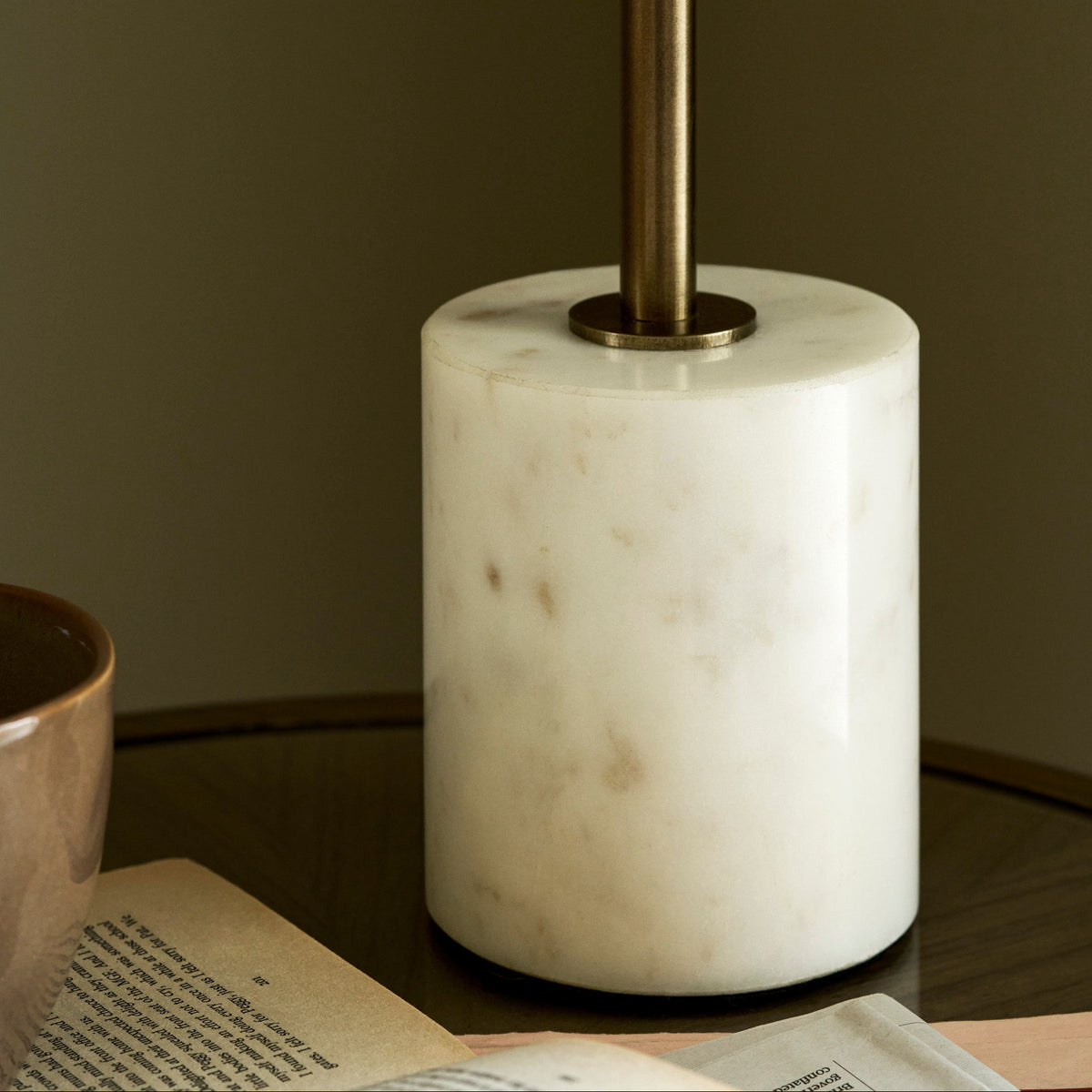 Close up of the Winsley brass and marble table lamp base on a wooden table with books