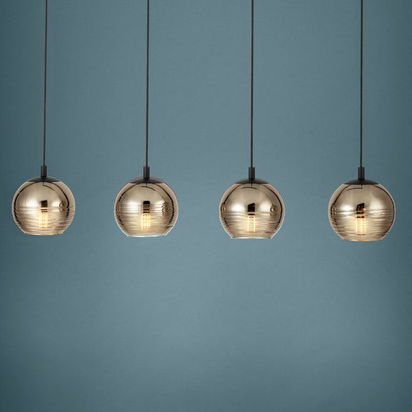 Four gold glass pendant lights with visible filaments hang against a blue-grey background. 