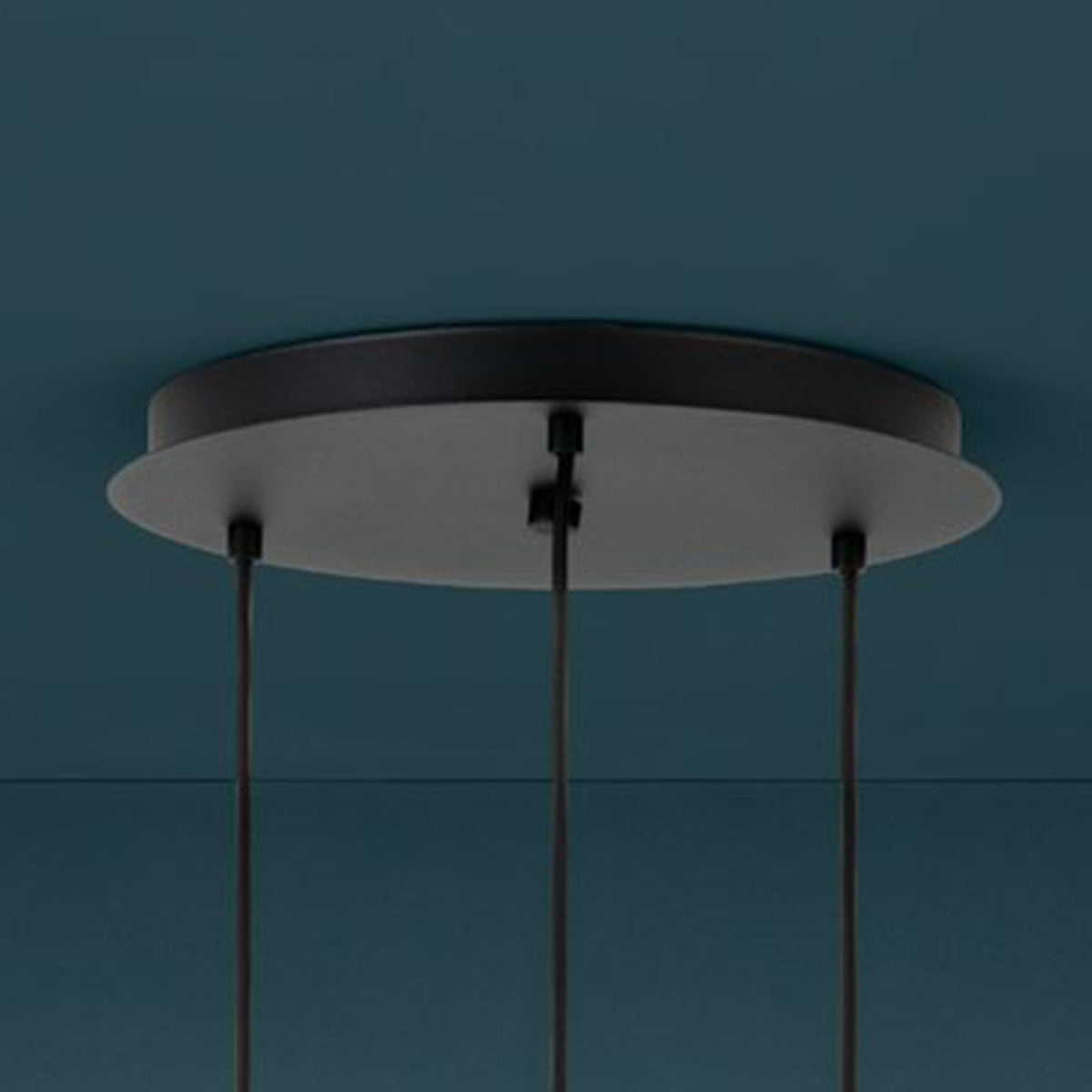 Black circular ceiling rose with three cables hanging down, against a dark teal ceiling.