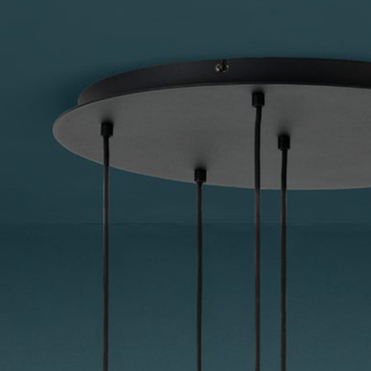 Close-up of a black ceiling rose with four black cables hanging down against a dark teal background.