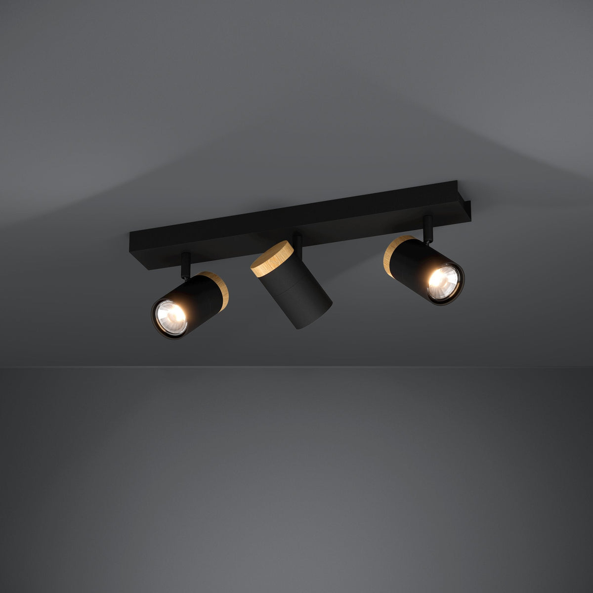 Three black and wood ceiling spotlights illuminate a dark grey room.