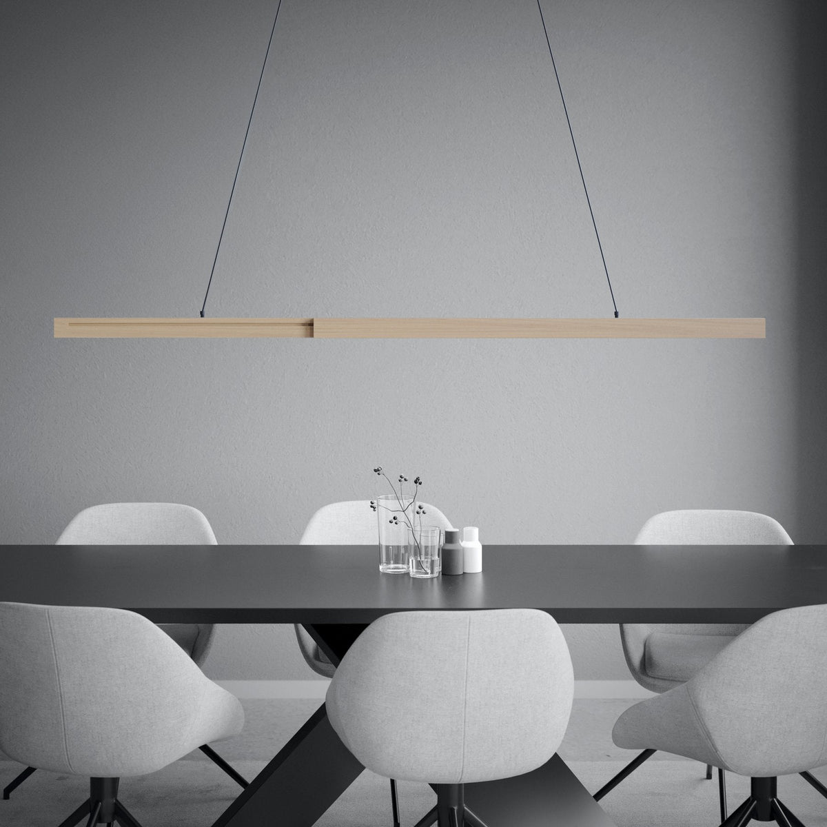 Wooden linear pendant light above a black dining table with light grey chairs