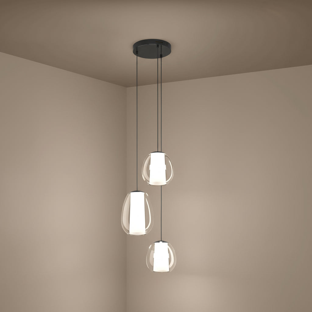 Three pendant lights with clear glass shades and white inner diffusers hanging from a dark ceiling plate