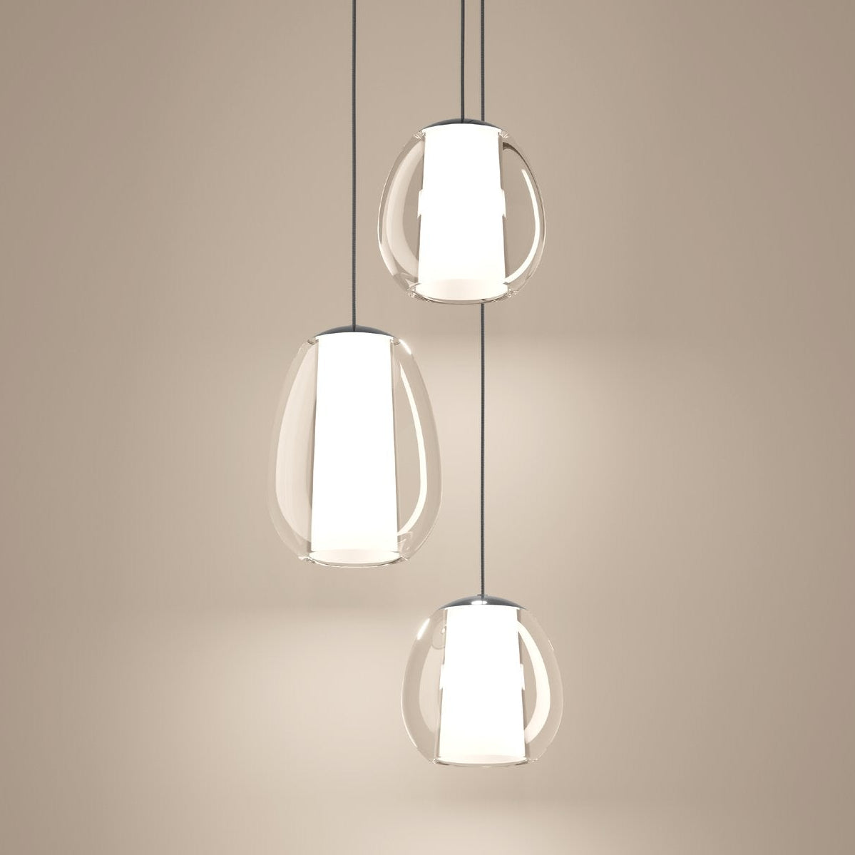 Three clear glass pendant lights with white cylindrical diffusers hanging against a light background