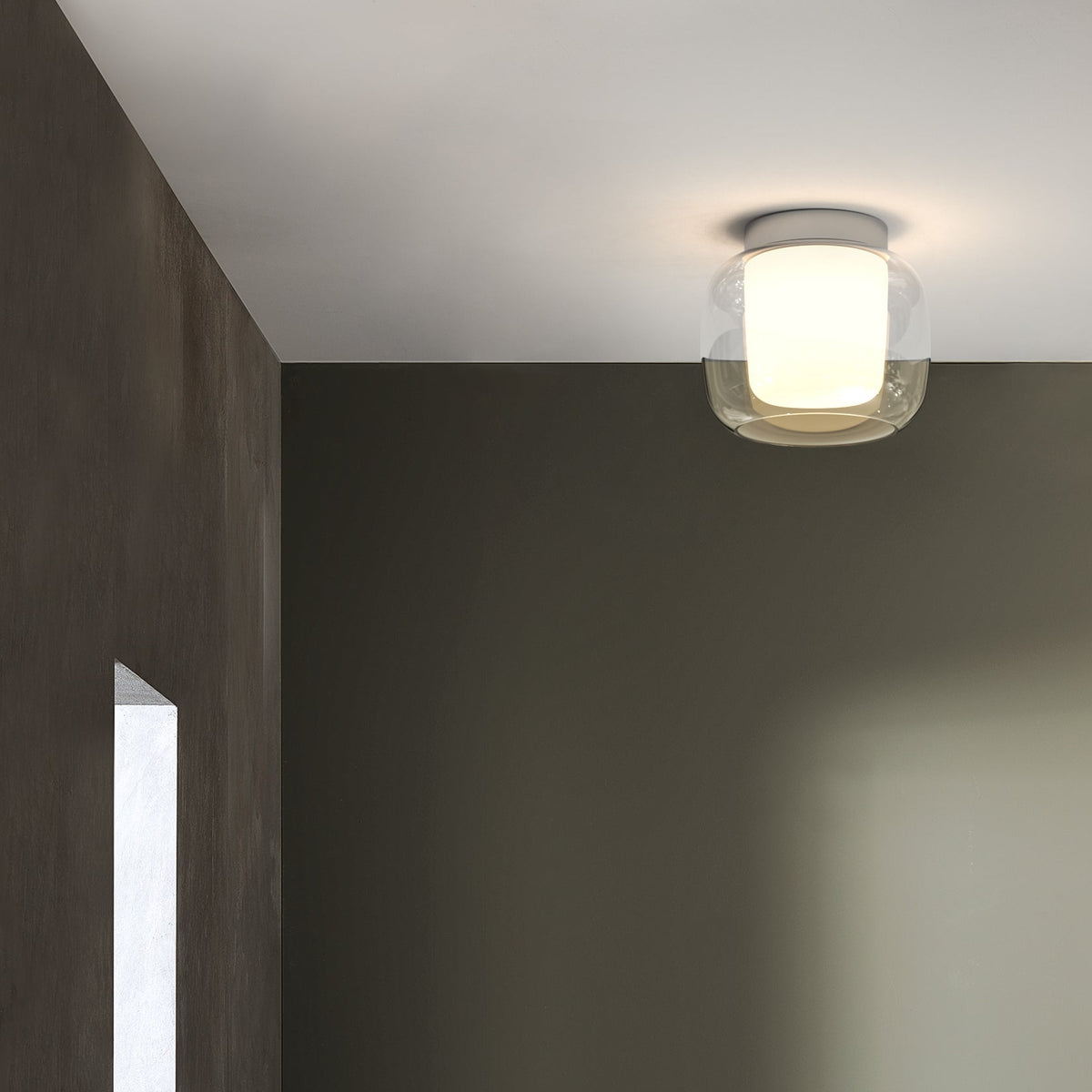 A ceiling light with a clear glass shade and a white inner diffuser illuminates a dark room