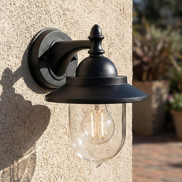 Black outdoor wall light with clear glass shade and exposed filament bulb