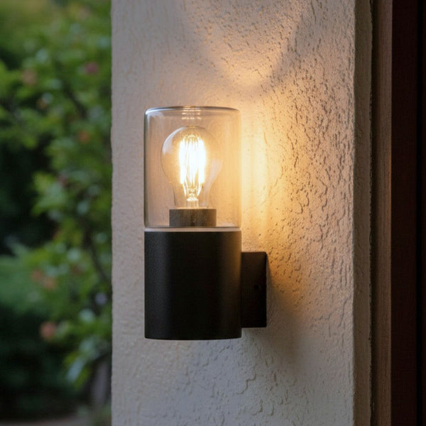 Black outdoor wall light with clear glass shade and exposed filament bulb
