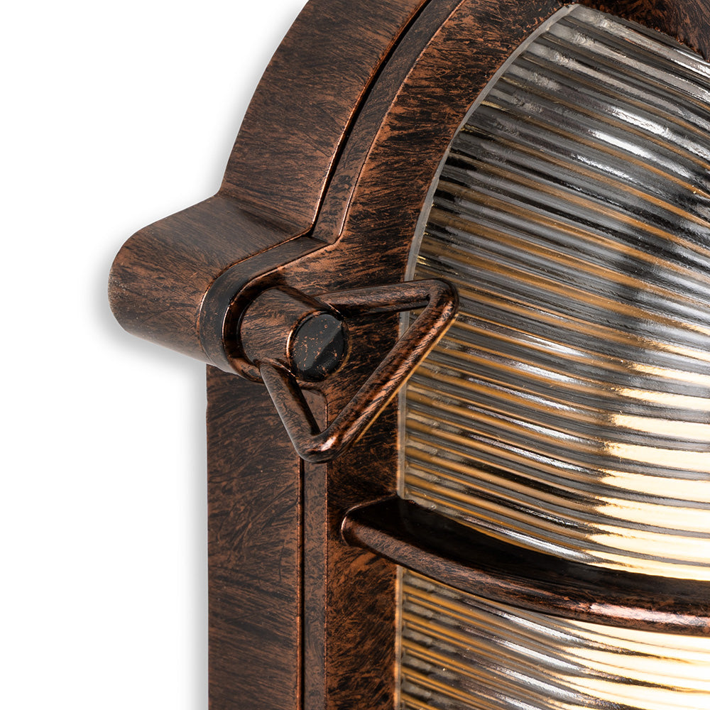 Close up of a bronze outdoor wall light with a ribbed glass shade