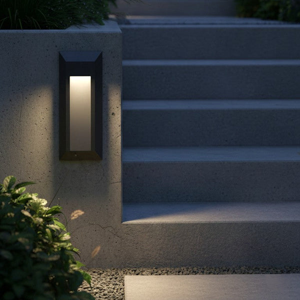 Rectangular outdoor wall light illuminating a concrete wall next to steps and plants