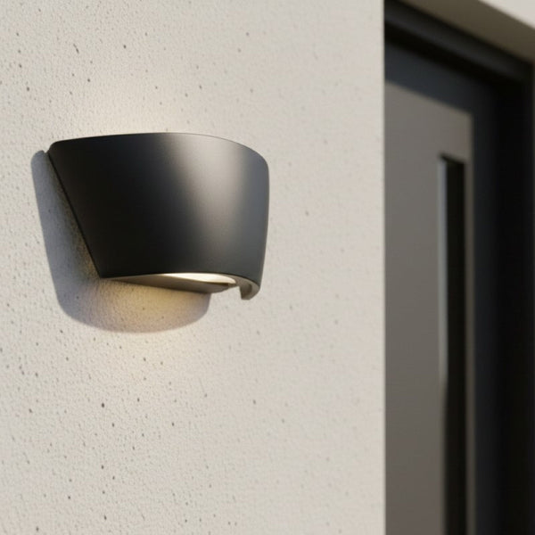 Black outdoor wall light with downward illumination on a textured wall