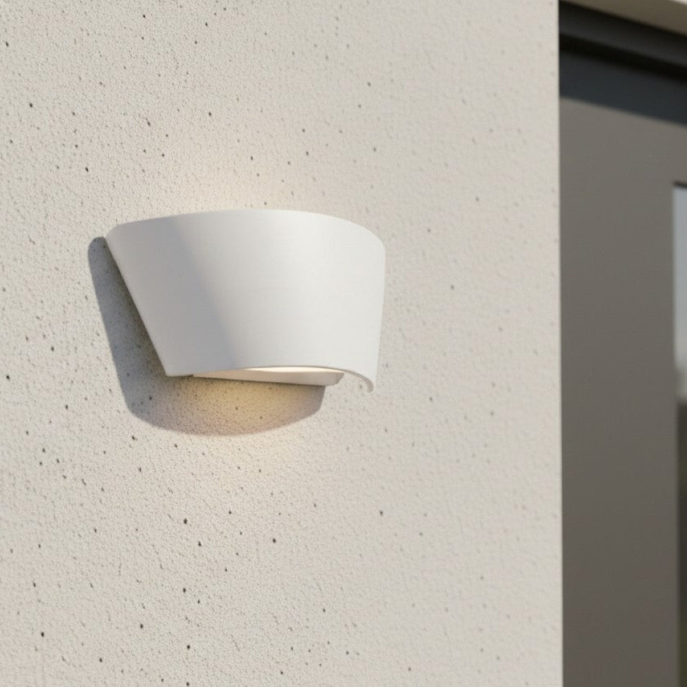 White outdoor wall light with a curved design, illuminating a textured white wall