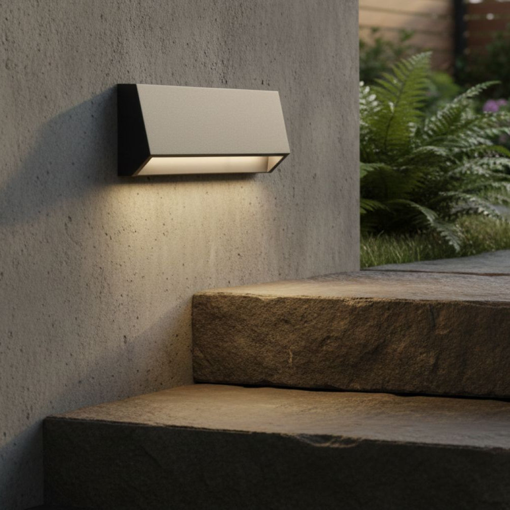 Rectangular outdoor wall light illuminating stone steps and a concrete wall