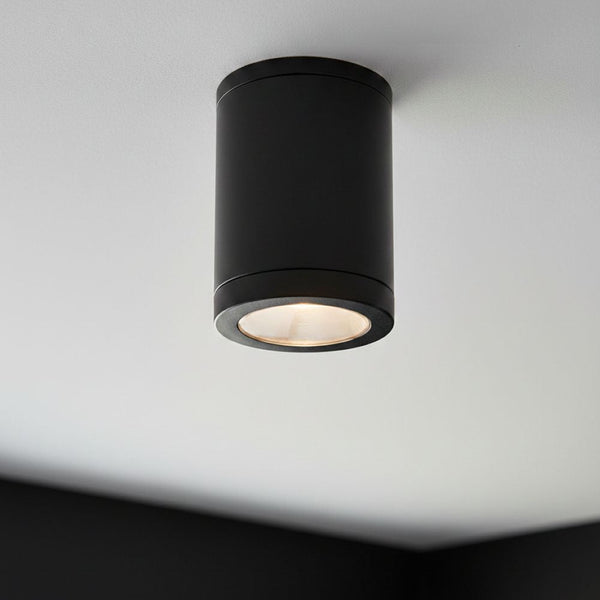 Black cylindrical ceiling light fixture with a warm glow