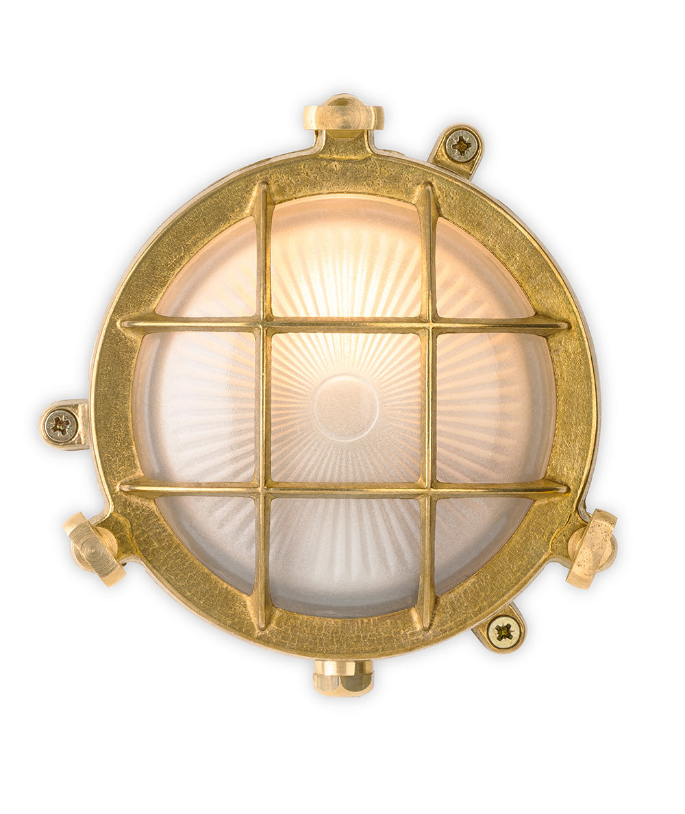 Round brass bulkhead light with a frosted glass diffuser and a protective brass grid