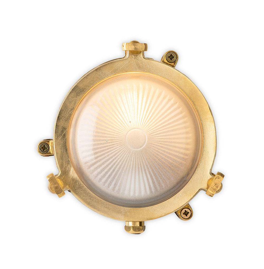 Round brass outdoor light with a clear glass lens and a sunburst pattern