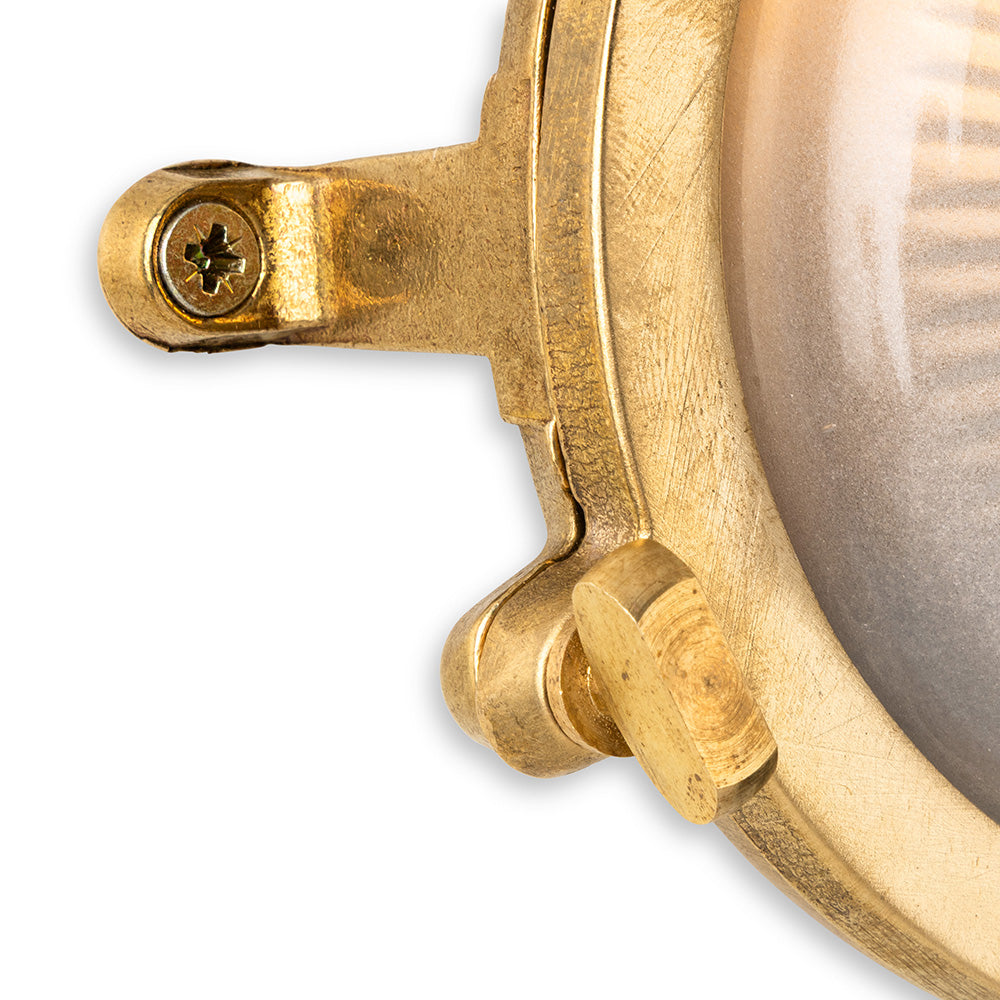 Close up of a brass porthole light fixture with a clear glass lens