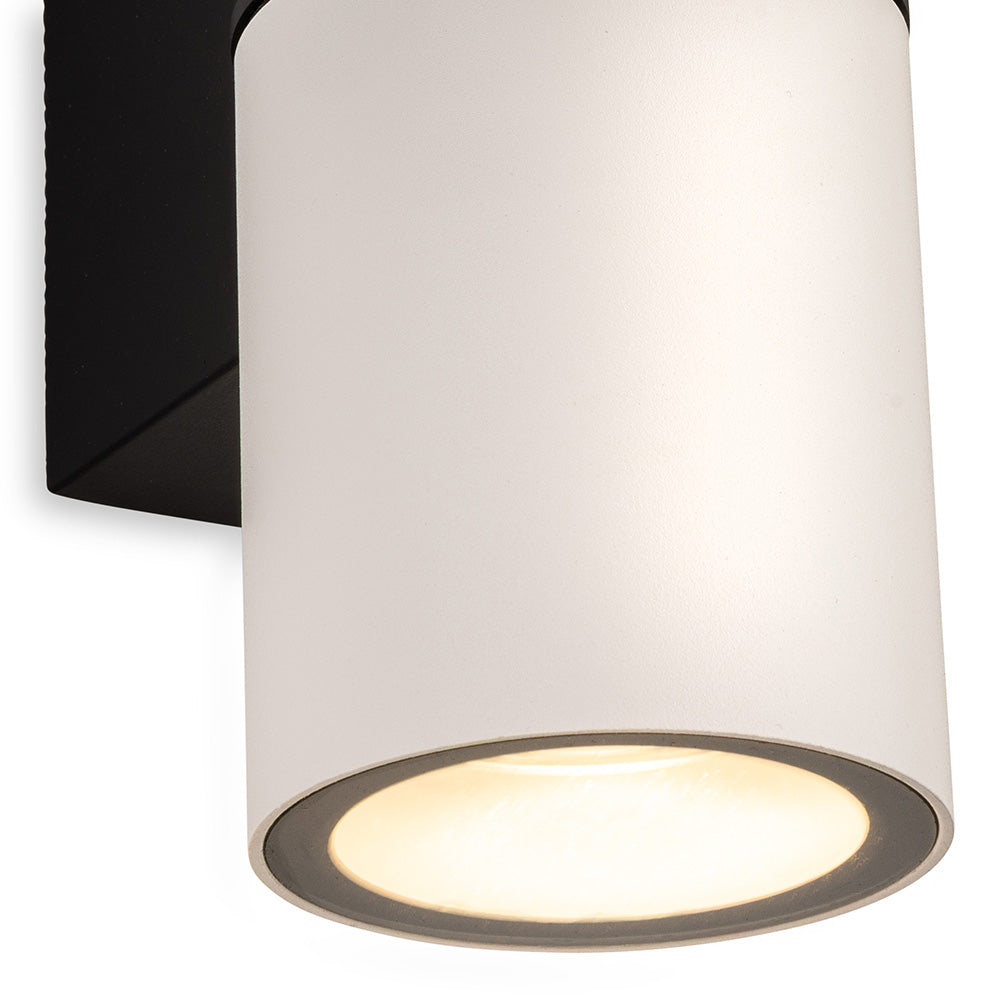White cylindrical wall light with a black base, emitting a warm glow from the bottom