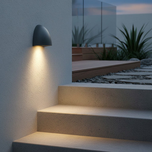 Outdoor wall light illuminating concrete steps and a garden path with pebbles and plants
