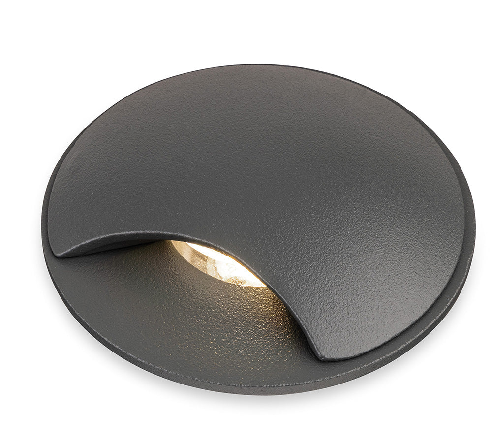 Round dark grey recessed ground light with a warm white glow