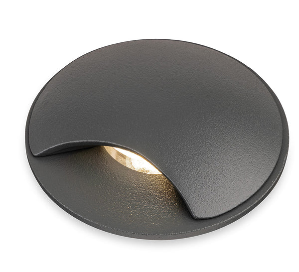 Round dark grey recessed ground light with a warm white glow