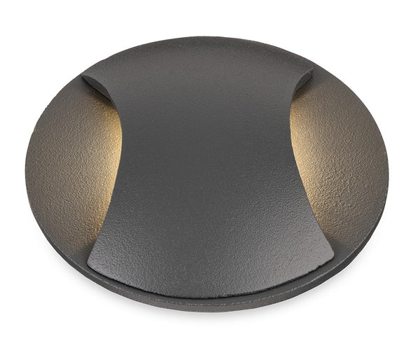Round dark grey outdoor light with two curved openings emitting warm light