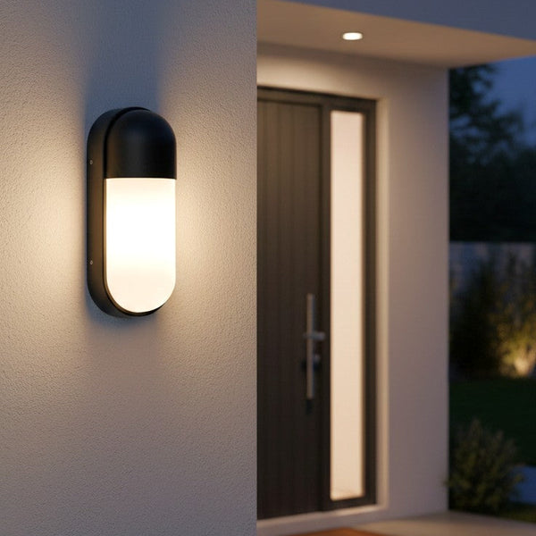 Black outdoor wall light with an opaque white diffuser, illuminating a modern home entrance at dusk
