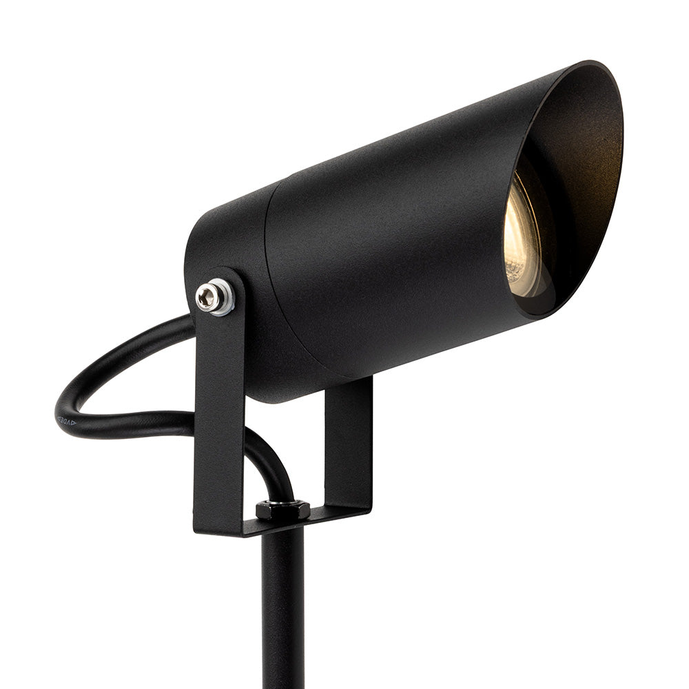 Black cylindrical outdoor spotlight with a warm light, mounted on a stake