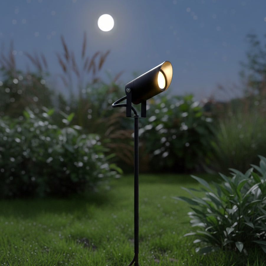 Black outdoor spotlight illuminates a garden at night under a full moon