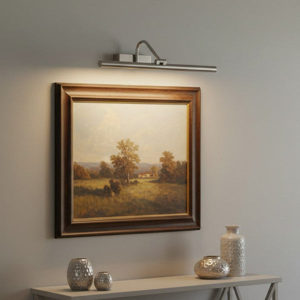 A painting of a landscape with trees and a house, illuminated by a picture light above it