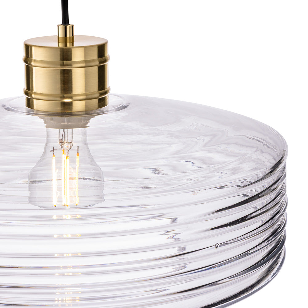 Close up of a clear glass pendant light with a brass fitting and exposed bulb