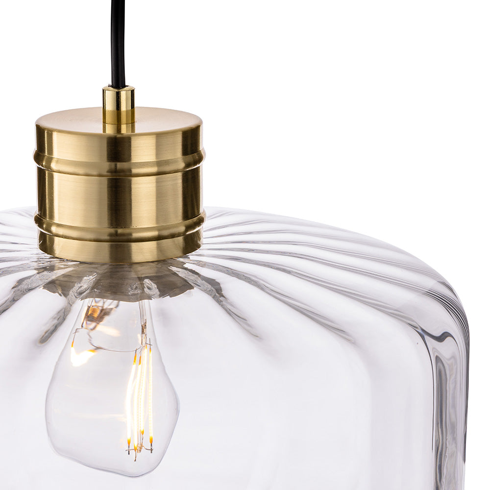 Close up of a clear glass pendant light with a brass fitting and exposed bulb