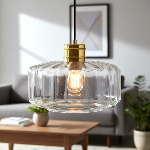 Clear fluted glass pendant light with a brass fixture and exposed filament bulb