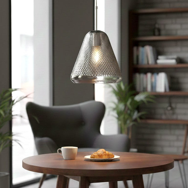 Textured glass pendant light above a wooden table with a coffee cup and croissants
