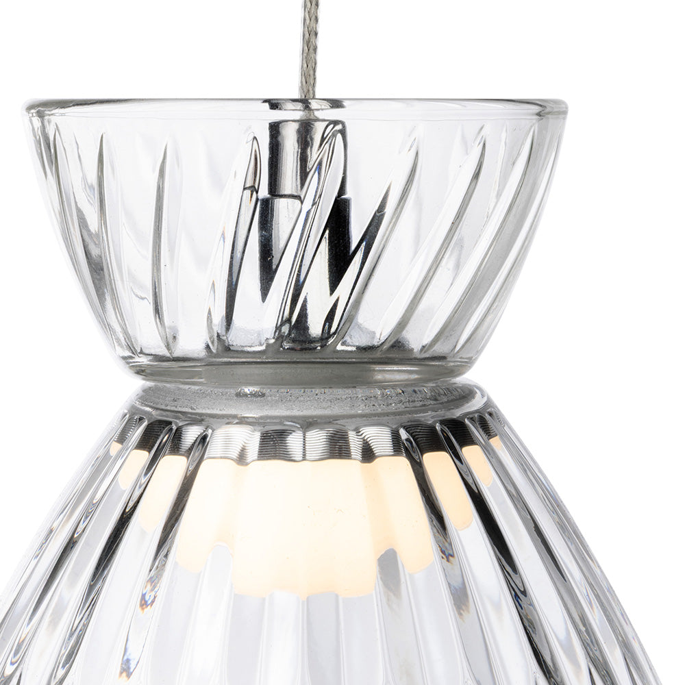 Close up of a clear glass pendant light with a ribbed design and a warm glow