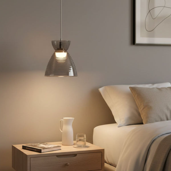 Ribbed glass pendant light above a wooden nightstand with a book, water pitcher, and glass
