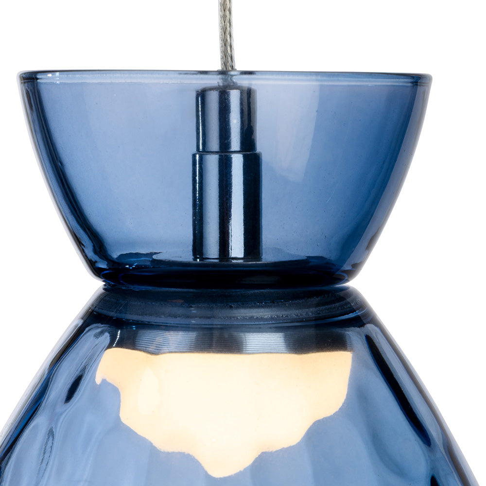 Blue glass pendant light with a silver cord and a warm glow from the bulb
