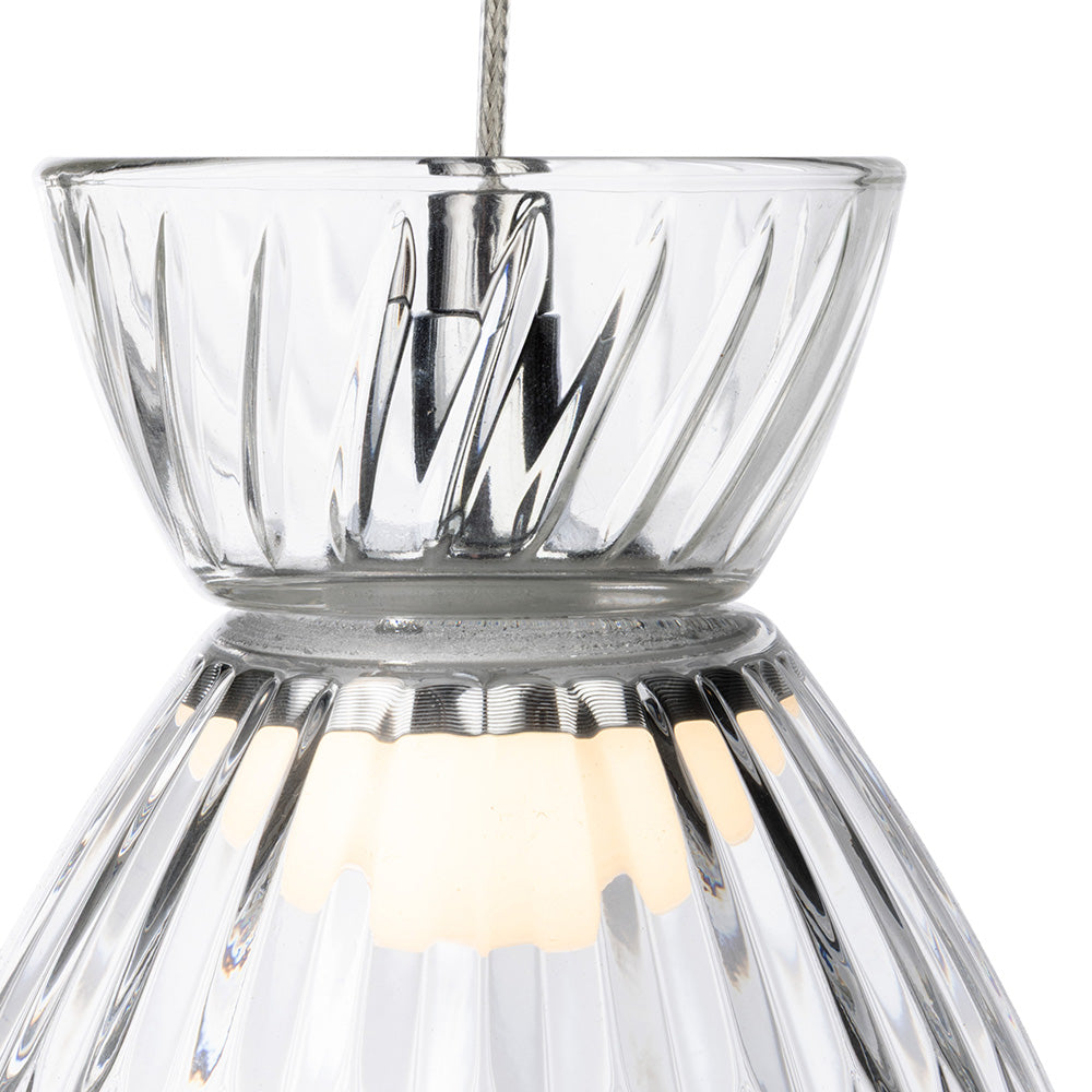 Clear glass pendant light with a ribbed design and a warm glowing bulb