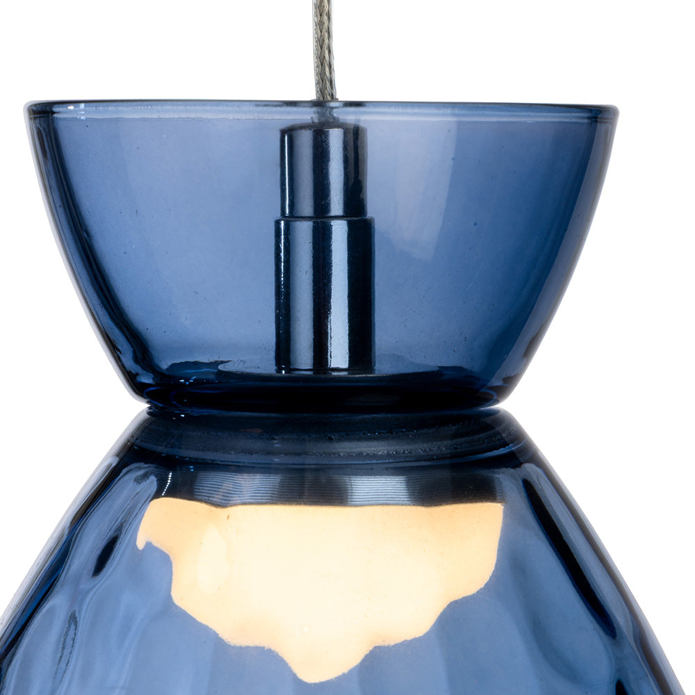 Close up of a blue glass pendant light with a light bulb glowing inside