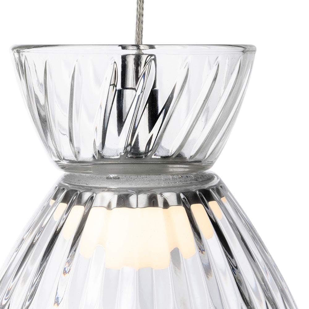 Close up of a clear glass pendant light with a ribbed texture and a warm glow