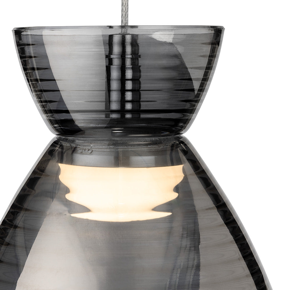 Close up of a grey glass pendant light with a light bulb glowing inside