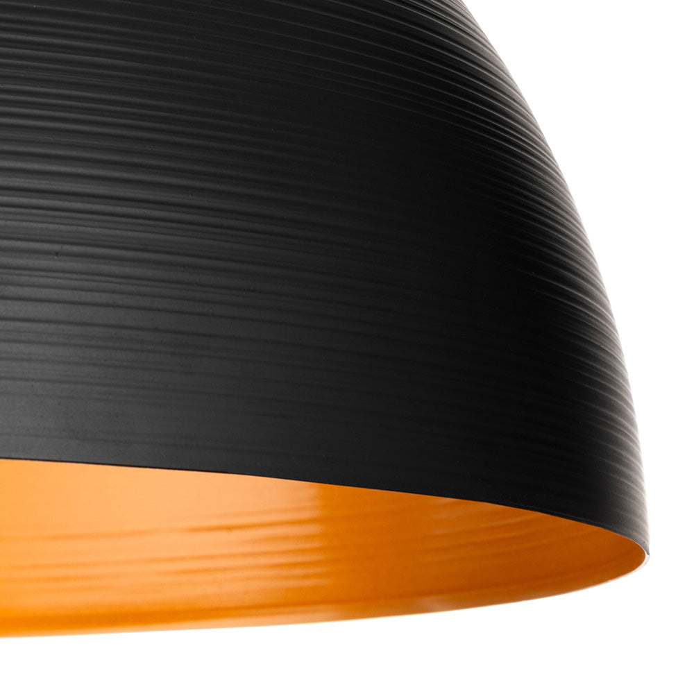 Close up of a black pendant light with a textured surface and a bright orange interior