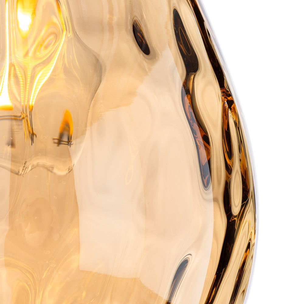 Close up of a wavy amber glass light fixture with a glowing bulb inside