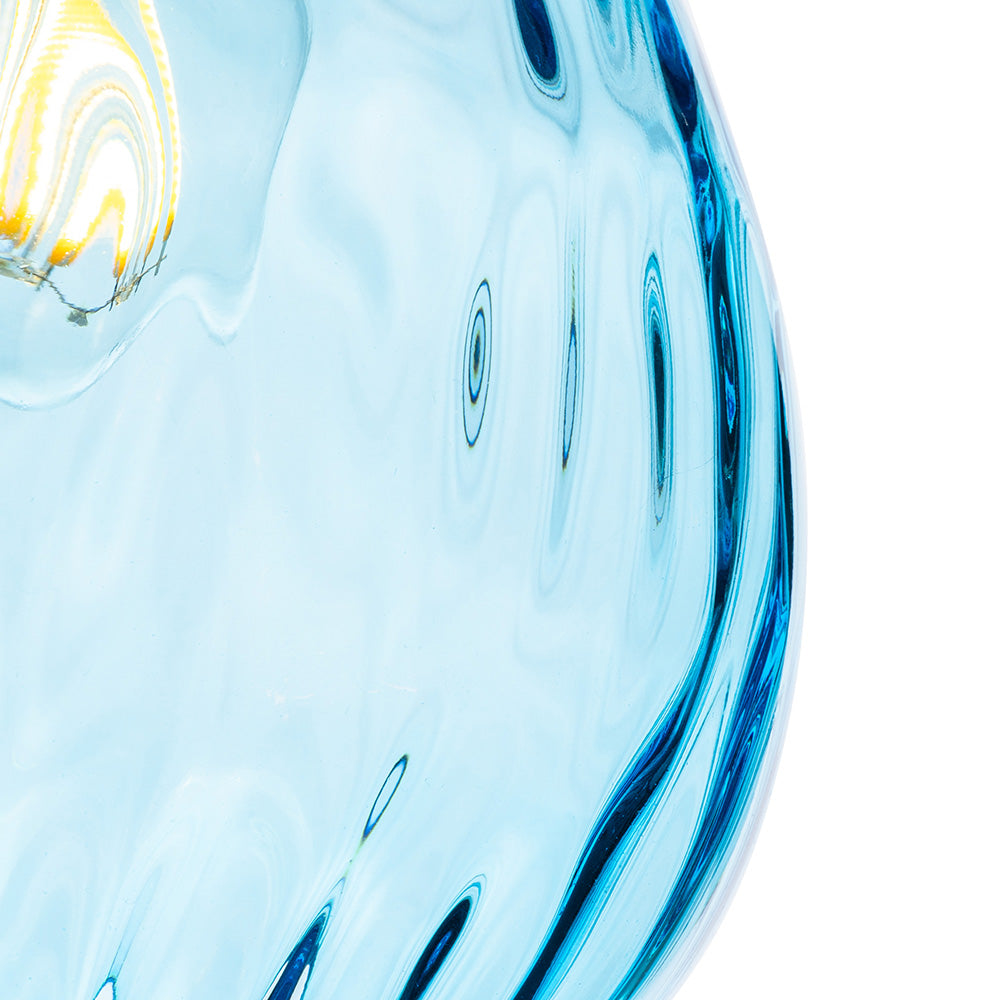 Close up of a light blue glass vase with dark blue swirls and a light reflection